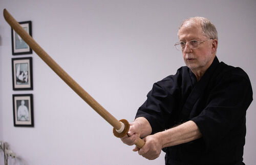A man holding a bokken while practicing iaido in Ann Arbor